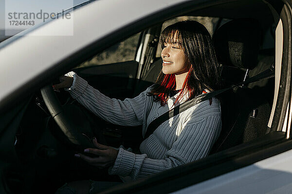 Lächelnde Frau am Steuer eines Autos während eines Ausflugs