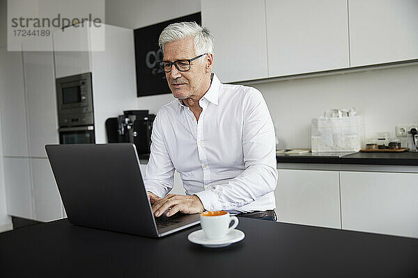 Ältere Berufstätige arbeiten am Laptop in der Cafeteria