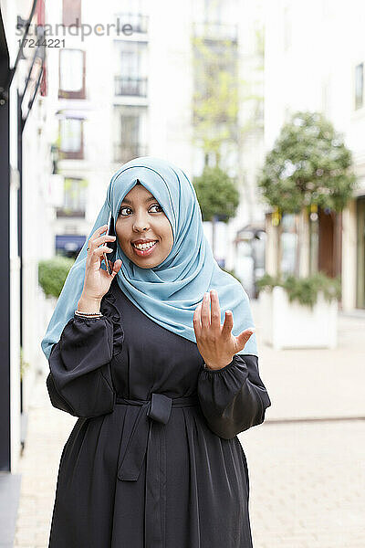Junge Frau gestikuliert beim Telefonieren mit dem Handy