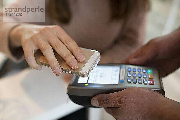 Frau bezahlt im Restaurant mit ihrem Smartphone