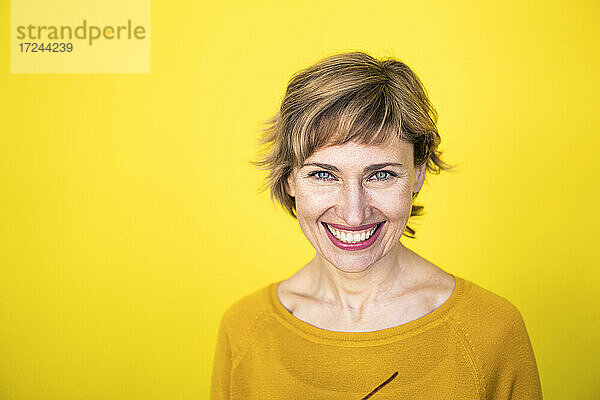 Lächelnde schöne Frau vor gelbem Hintergrund
