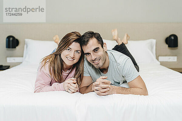 Lächelndes Paar auf dem Bett im Hotelzimmer