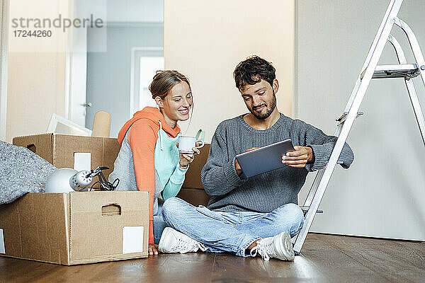 Junges Paar diskutiert über digitales Tablet in der neuen Wohnung