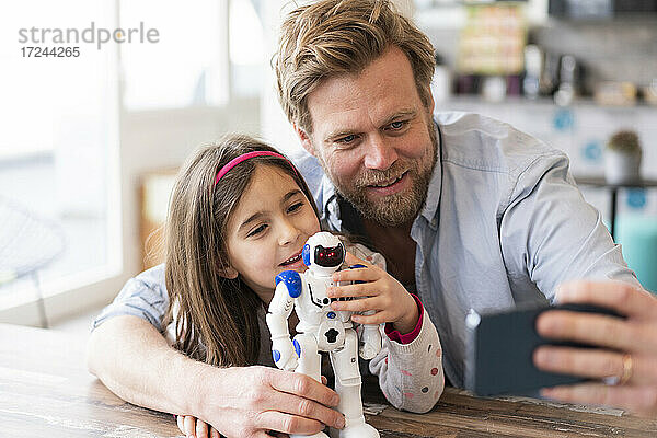 Vater nimmt Selfie durch Handy mit Tochter und Roboter Spielzeug zu Hause