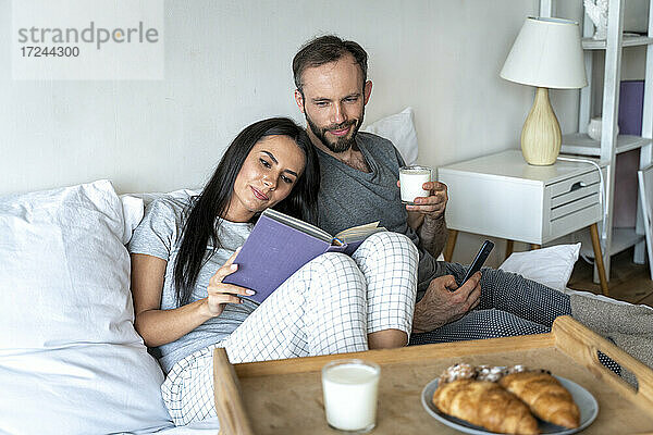 Mann und Frau frühstücken zu Hause auf dem Bett