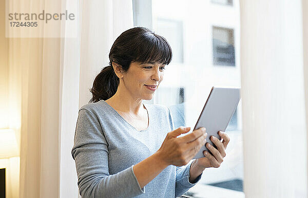 Lächelnde Frau mit digitalem Tablet in einer Hotelsuite
