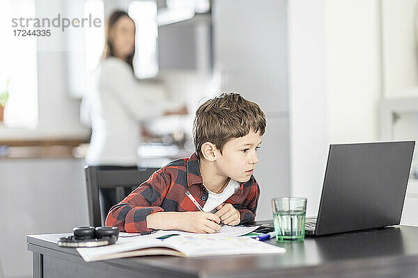 Junge  der sich beim Lernen auf seinen Laptop zu Hause konzentriert