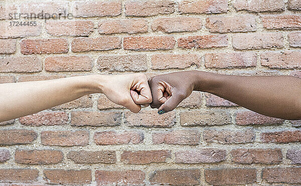 Weibliche Freunde geben Fauststoß durch Ziegelwand