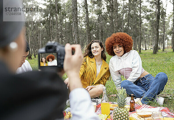 Männliche und weibliche Freunde fotografieren beim Feiern im Wald