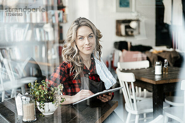 Mittlere erwachsene Frau  die am Fenster eines Cafés sitzt