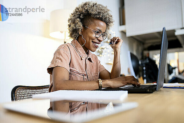 Lächelnde weibliche Fachkraft  die einen Laptop bei der Arbeit im Heimbüro benutzt