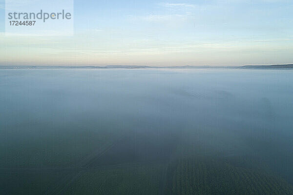Drohnenansicht der in dichten Nebel gehüllten Landschaft in der Morgendämmerung