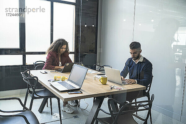 Männliche und weibliche Fachkräfte arbeiten an einem Laptop in einem Coworking-Büro
