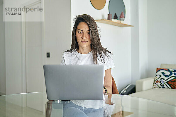 Mittlere erwachsene Frau benutzt Laptop zu Hause