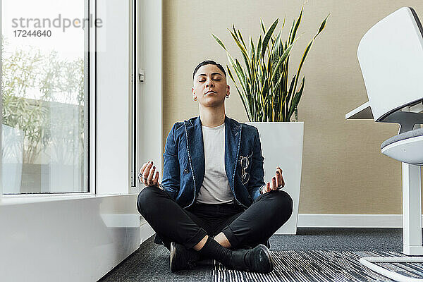 Junge Unternehmerin beim Meditieren im Büro sitzend