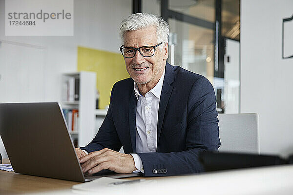 Unternehmerin mit Laptop lächelnd im Büro