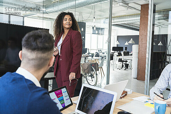 Junge Geschäftsfrau schaut während einer Besprechung im Büro weg