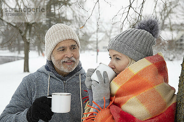 Mann sieht Frau an  die im Winter Tee in einem Becher trinkt