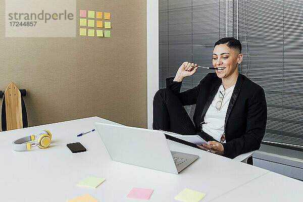 Unternehmerin schaut im Büro sitzend auf ihren Laptop