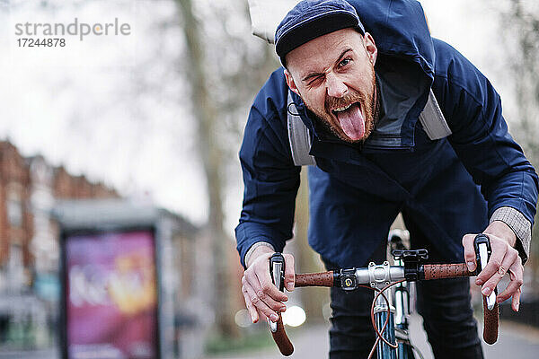 Junger Mann streckt beim Fahrradfahren die Zunge heraus