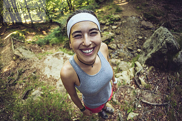 Lächelnde Frau mit Stirnband im Wald stehend