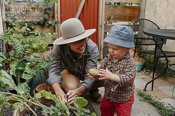 Kleiner Junge mit Kartoffel bei seiner Mutter im Hinterhof
