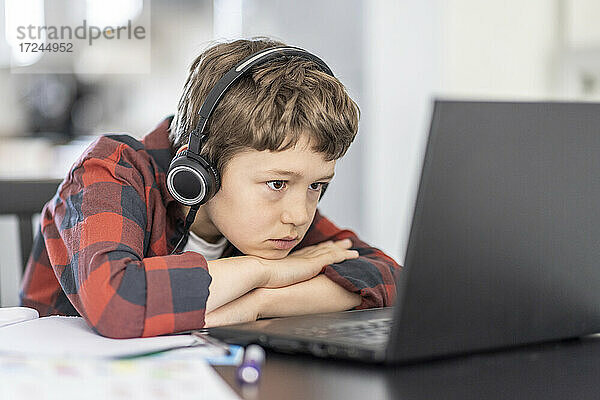 Junge nimmt an Online-Kursen über Laptop teil  während er zu Hause e-learning betreibt