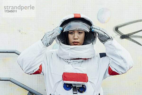 Weibliche Astronautin mit Helm an einer Wand stehend