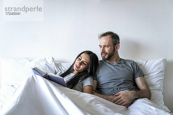 Mann und Frau lesen Buch auf dem Bett zu Hause