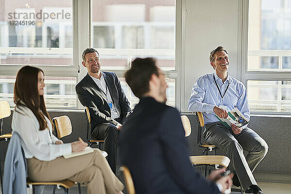 Lächelnder männlicher Unternehmer mit Kollegen in einem Schulungskurs