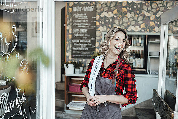 Fröhliche Geschäftsfrau vor dem Eingang eines Cafés