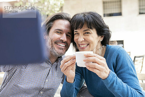 Reifer Mann nimmt Selfie auf Handy mit Frau auf Terrasse