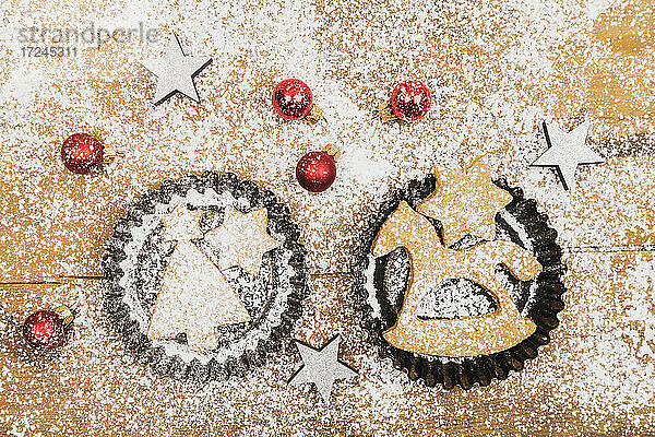 Weihnachtsschmuck und frische  selbstgebackene Kekse auf einer Holzunterlage