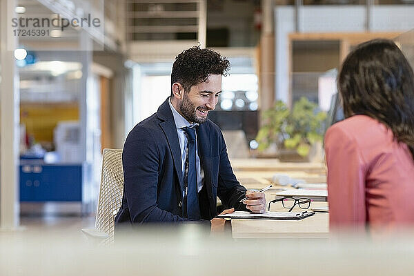 Lächelnder Geschäftsmann bei der Vertragsunterzeichnung in einem Coworking-Büro