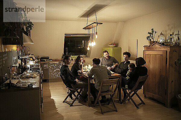 Männliche und weibliche Freunde unterhalten sich am Esstisch in der Küche