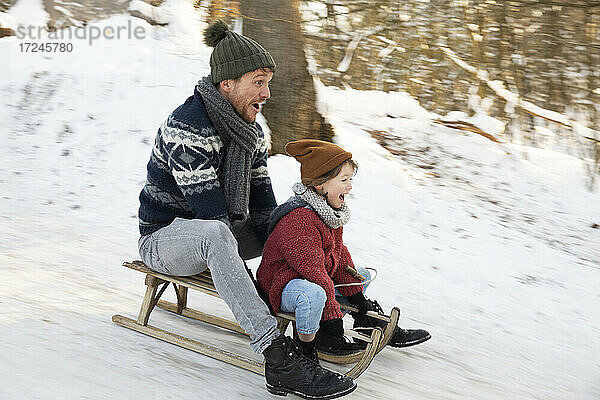 Vater und Sohn beim Schlittenfahren im Winter
