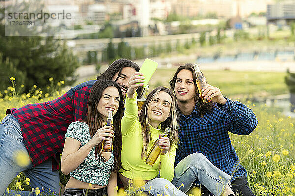 Frau nimmt Selfie mit männlichen und weiblichen Freunden beim Bier auf Feld in der Natur