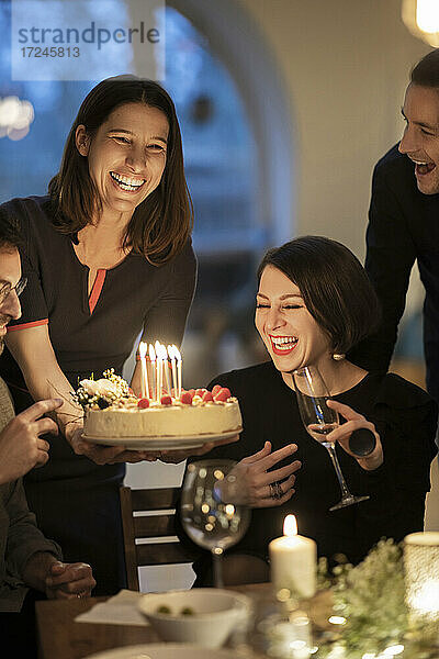 Männliche und weibliche Freunde lachen während einer Geburtstagsfeier zu Hause