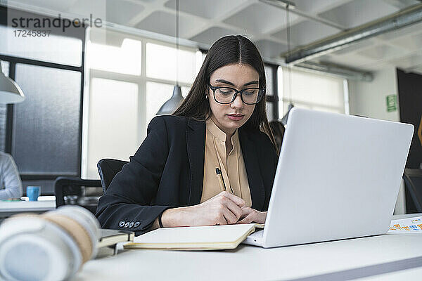 Geschäftsfrau  die im Coworking-Büro eine Geschäftsstrategie in ihrem Tagebuch festhält