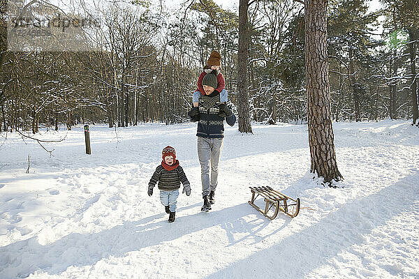 Vater geht im Winter mit seinen Söhnen im Schnee spazieren