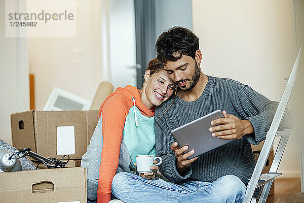 Junges Paar nutzt digitales Tablet in der neuen Wohnung