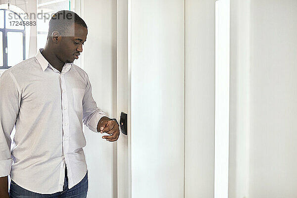 Geschäftsmann scannt Smartwatch  während er am Eingang eines Büros steht