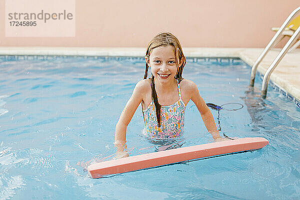 Lächelndes Mädchen mit Schwimmflügel im Pool
