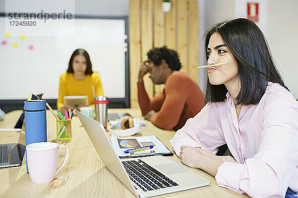 Kreative Geschäftsfrau hat Spaß mit Stift im Büro