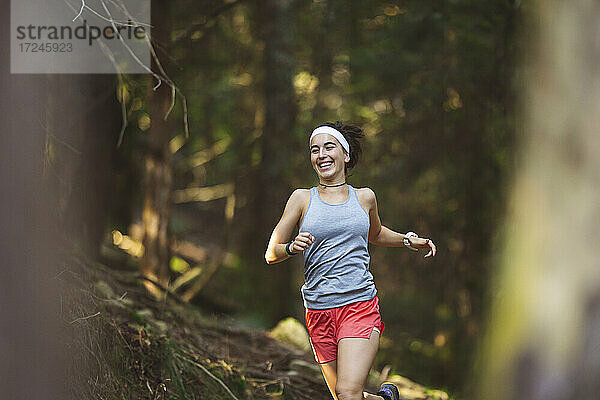 Lächelnde Frau in Sportkleidung beim Laufen im Wald