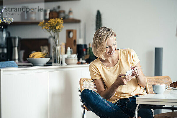 Lächelnde Frau  die zu Hause ein Mobiltelefon benutzt