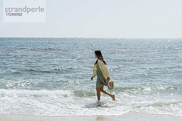 Frau mit Strohhut beim Spaziergang im Meerwasser am Wochenende