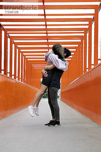 Teenager  der seine Freundin auf einer orangefarbenen Brücke abholt