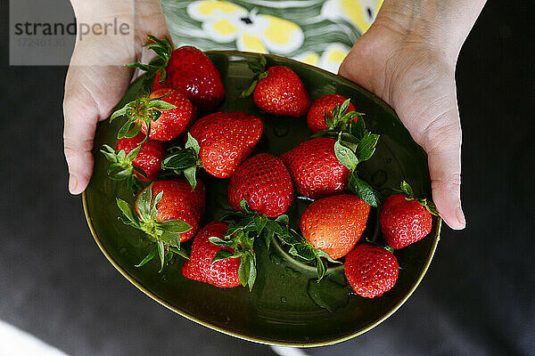 Frau hält Teller mit frischen Erdbeeren
