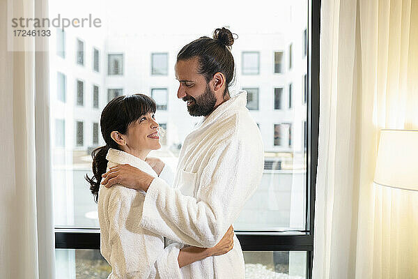 Älteres Paar in Bademänteln umarmt sich in einer Hotelsuite